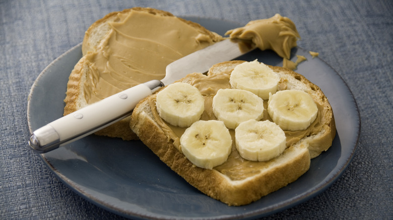 Making peanut butter banana sandwich on blue plate