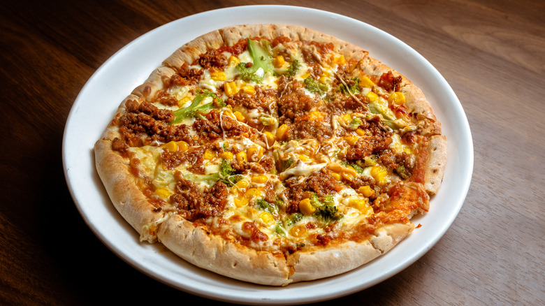 Pizza topped with Bolognese sauce, cheese, corn, and broccoli