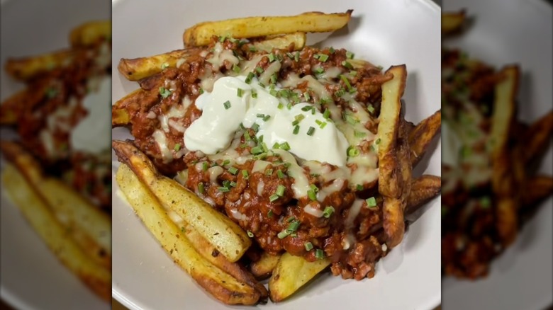 Fries topped with Bolognese sauce, melted cheese, sour cream, and chopped chives