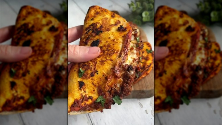 Hand holding taco filled with Bolognese sauce