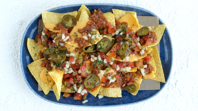 Plate of nachos topped with Bolognese sauce, cheese, salsa, and pickled jalapeños