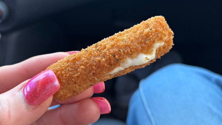 Fingers holding White Castle Mozzarella Cheese Stick in car