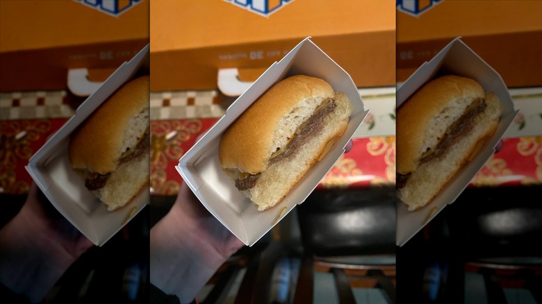 Hand holding White Castle Original Slider in carton
