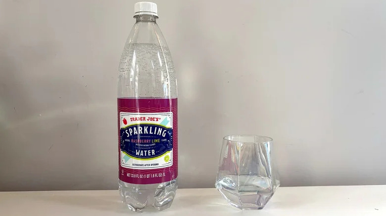 Bottle of Raspberry Lime Sparkling Water next to glass