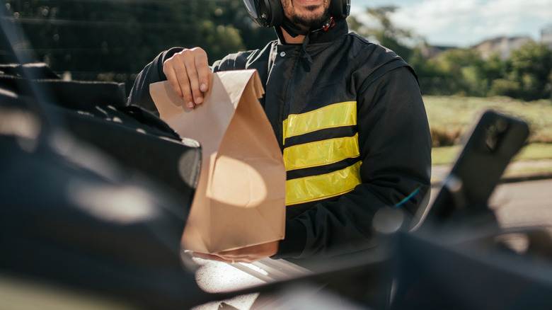 Delivery person taking a package out of their thermal backpack