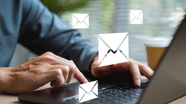 close up of hands typing on laptop with email logos