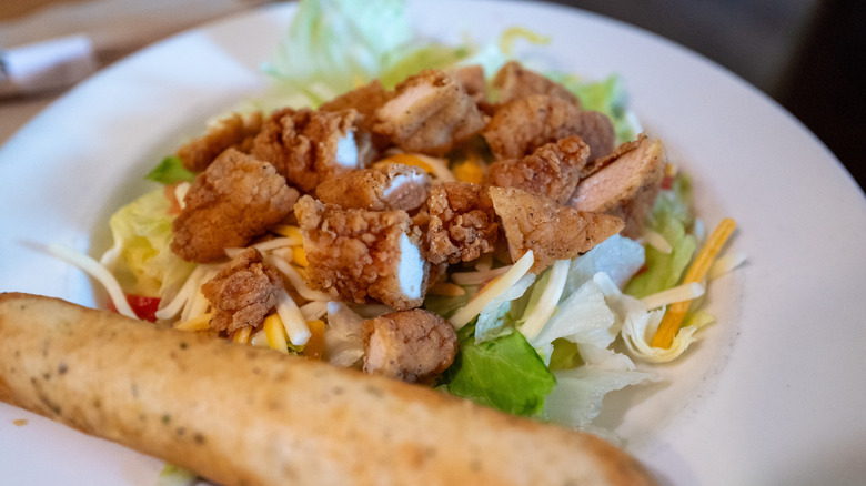 Close-up of an Applebee's chicken salad meal with breadstick