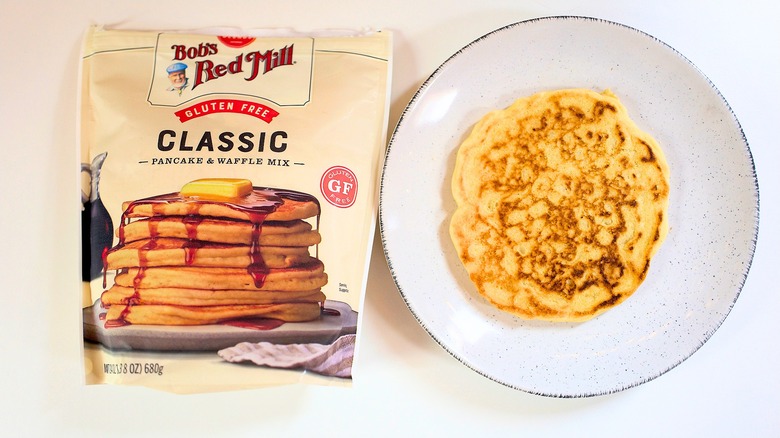 Overhead shot of bag of Bob's Red Mill Gluten Free Classic Pancake Mix next to pancake on white plate