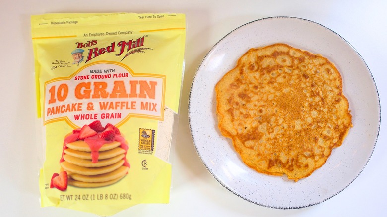 Overhead shot of bag of Bob's Red Mill 10-Grain Pancake Mix next to pancake on white plate