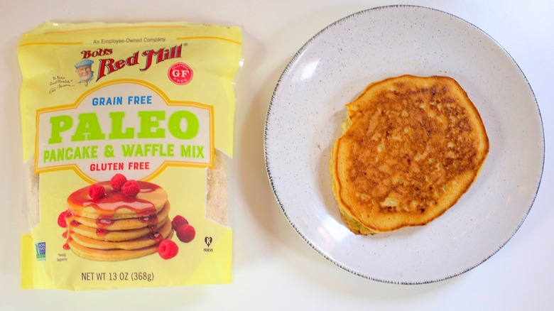 Overhead shot of bag of Bob's Red Mill Paleo Pancake Mix next to pancake on white plate