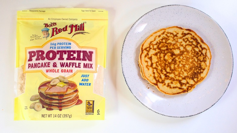 Overhead shot of bag of Bob's Red Mill Protein Pancake Mix next to pancake on white plate
