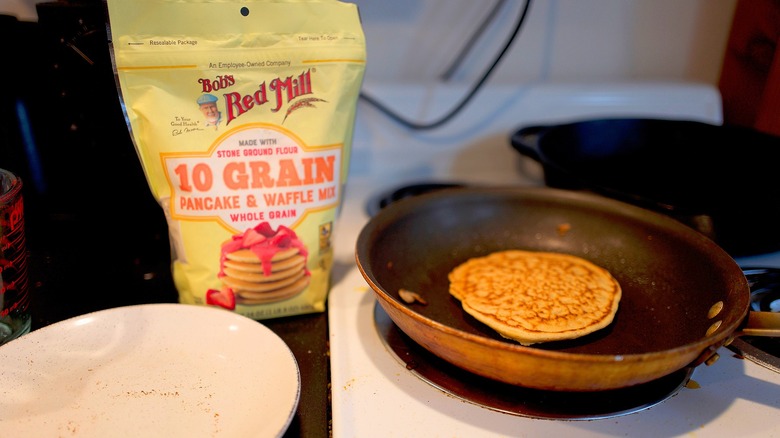 Bag of Bob's Red Mill 10-Grain pancake mix next to pancake frying in pan
