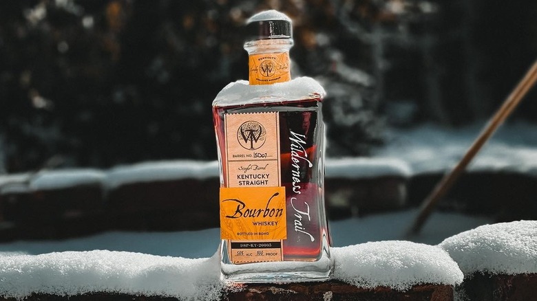 Wilderness Trail High Rye Bourbon perched on a wall outside and covered in snow