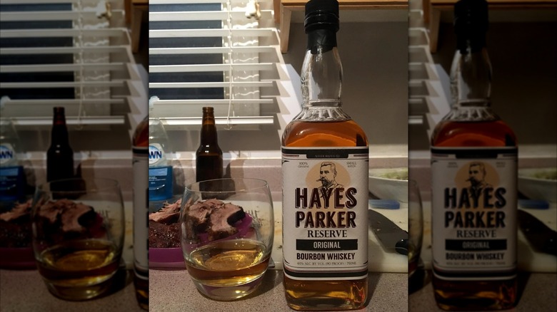 A bottle of Hayes Parker placed on a kitchen counter next to a filled glass