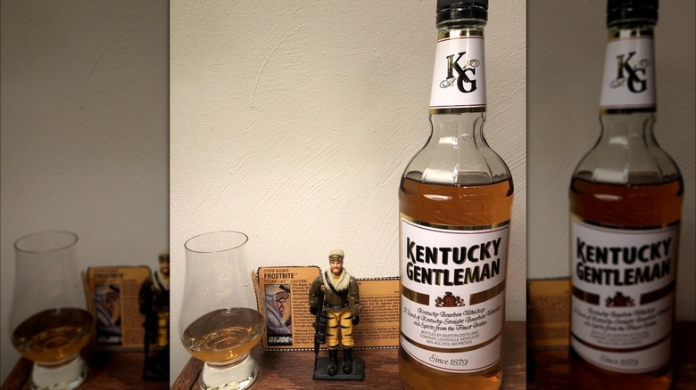 A bottle of Kentucky Gentleman shown next to a filled glass and a toy figurine