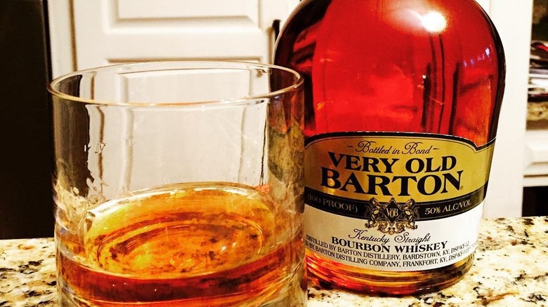 A bottle of Very Old Barton shown on a kitchen countertop with a filled glass tumbler next to it