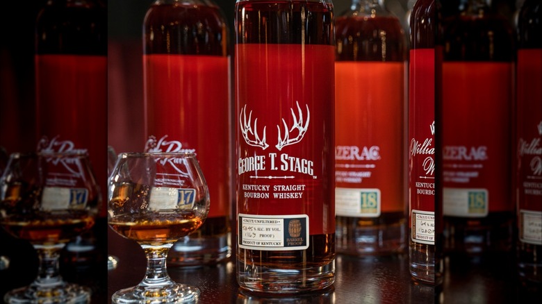A bottle of George T. Stagg with bottles around it next to a filled glass