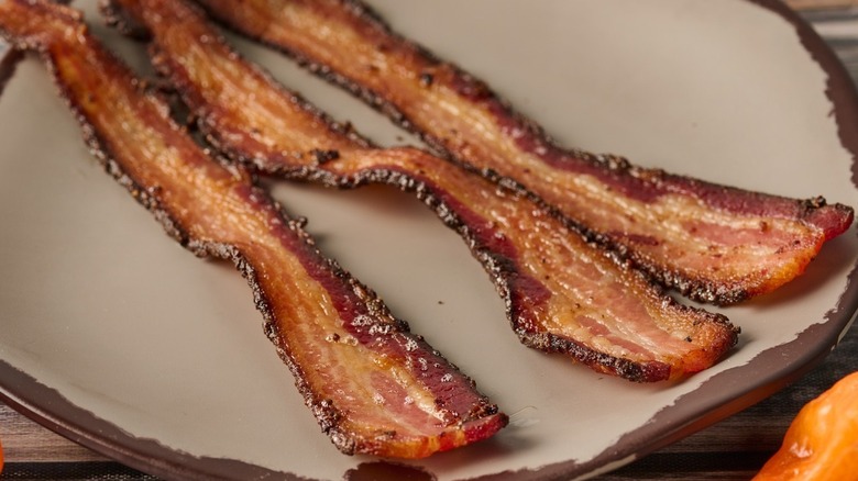 Three slices of habanero infused cooked bacon on a white plate