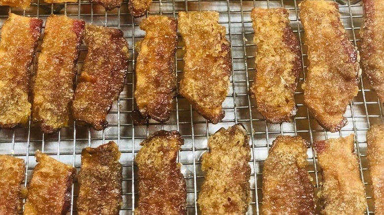 Cooked candied bacon lined up on a sheet
