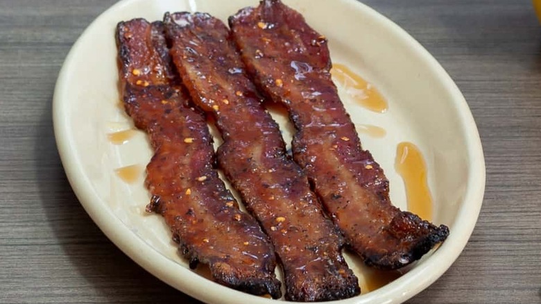 Three pieces of bacon with syrup and chili flakes