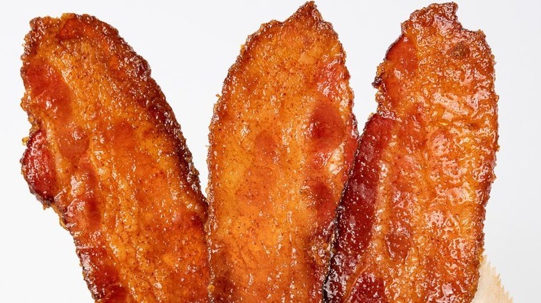 Three pieces of crispy cooked bacon on white background