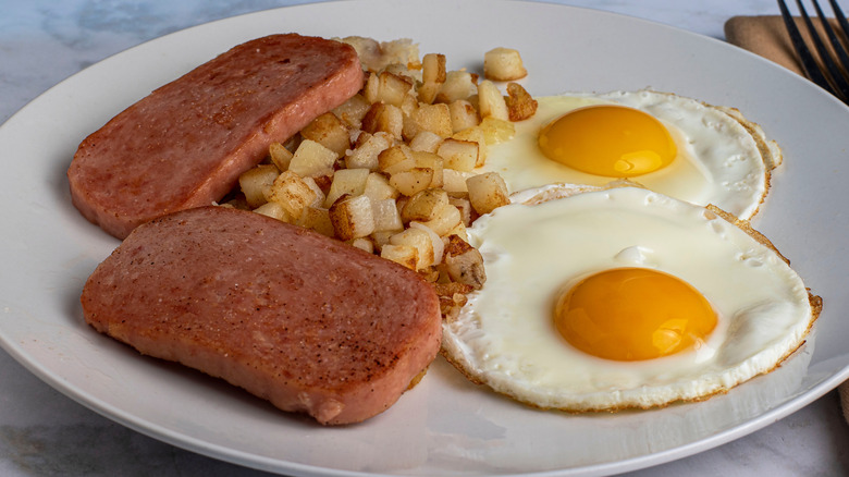 fried eggs served with fried spam and hash browns