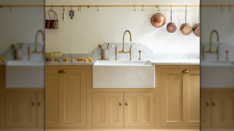 A butter-yellow kitchen with brass fittings