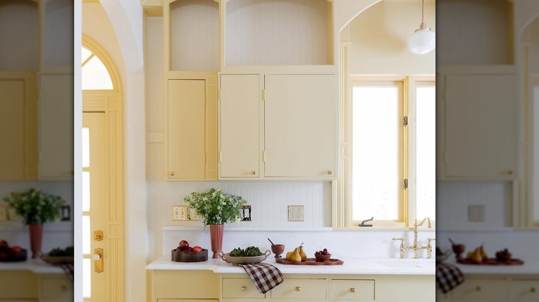 A butter-yellow kitchen with cabinet arches