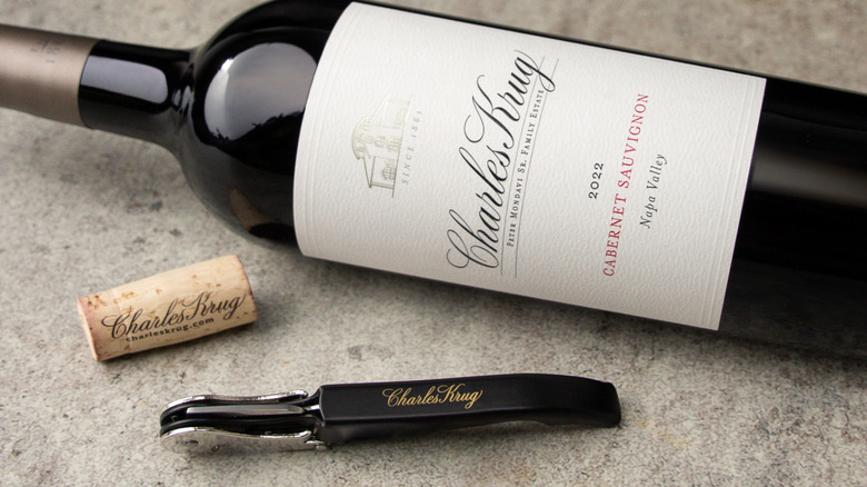 Red wine bottle of Charles Krug Cabernet Sauvignon lying on side with corkscrew