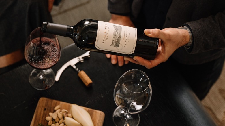 A person pouring red wine into glass