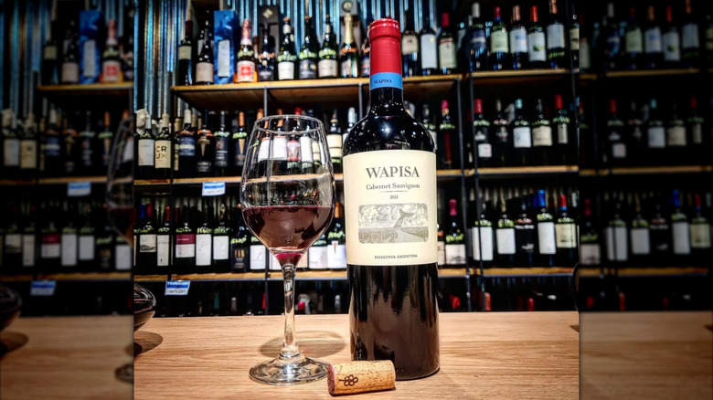 Bottle of Wapisa Cabernet Sauvignon red wine on counter with wine glass