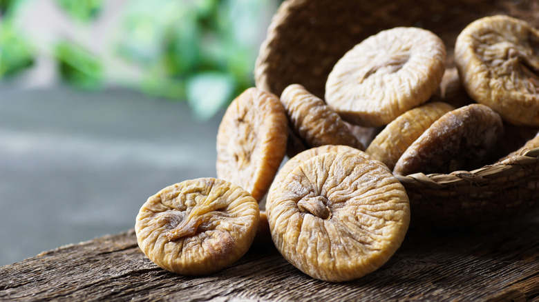 Sun-dried figs spilling from wooden bowl