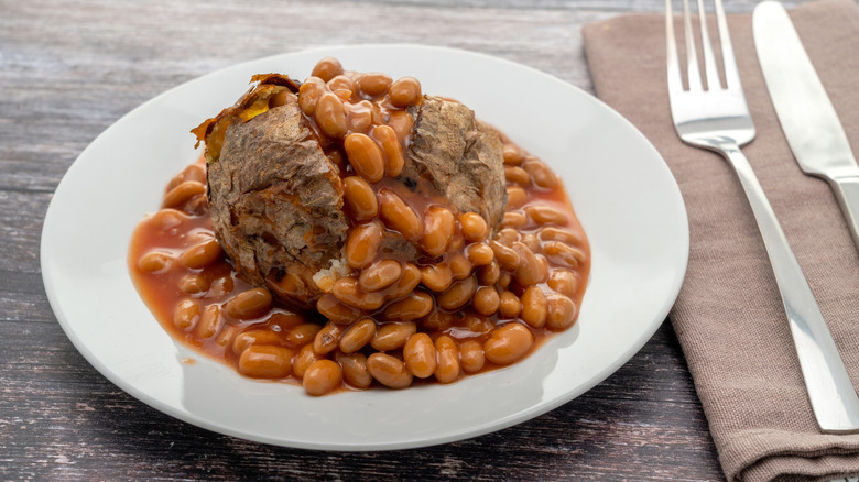 Baked potato on plate, topped with baked beans
