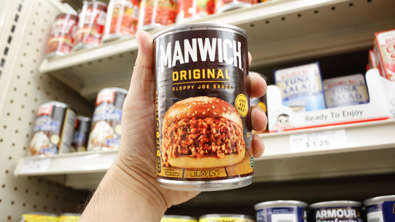 Hand holding can of sloppy Joe sauce in grocery store