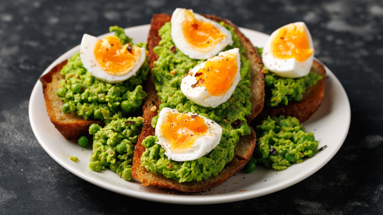 Smashed peas on slices of sourdough toast with soft-boiled eggs