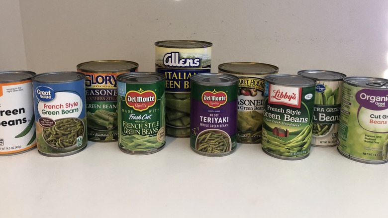 10 different cans of green beans in a line.