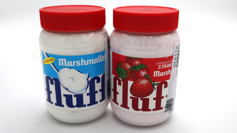 Two jars of plain and strawberry-flavored marshmallow fluff on white background