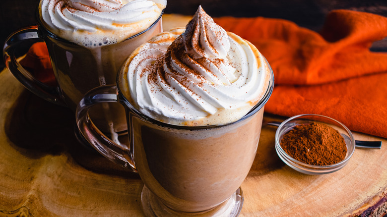 Mugs of hot chocolate with whipped cream and cinnamon