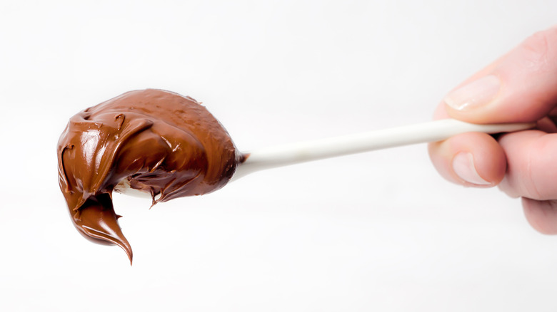 Hand holding spoonful of Nutella