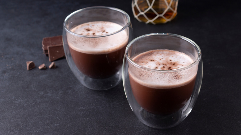 Two glasses of hot chocolate with bottle of rum in background