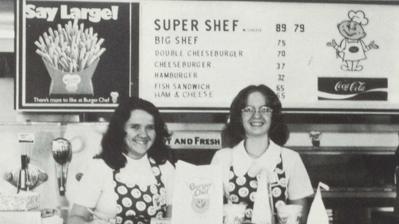 Black and white image of female workers at Burger Chef in front of menu