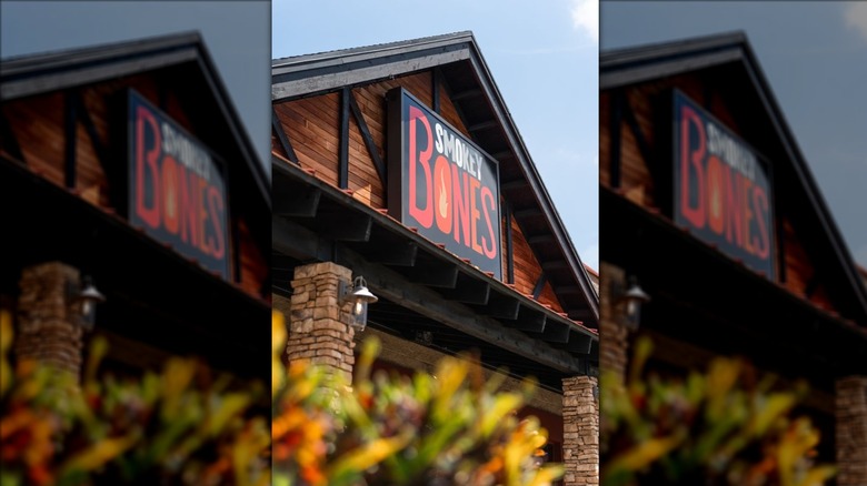 Smokey Bones Bar & Fire Grill sign on wooden building against blue sky