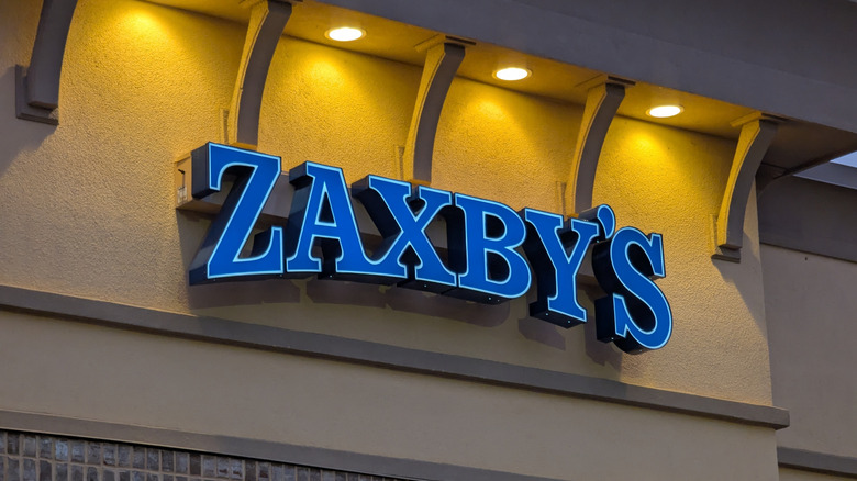 Zaxby's blue logo on the side of the restaurant building under yellow lights