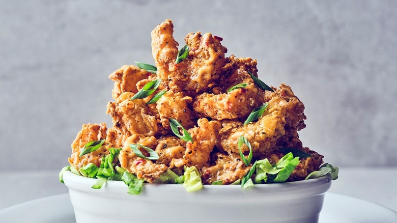 Crispy Bang Bang Shrimp piled into white bowl and garnished with chopped green onion