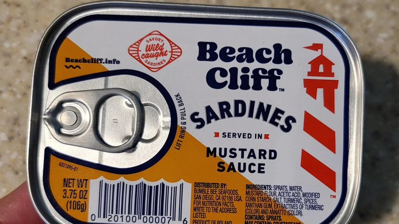 close up of hand holding a tin of Beach Cliff sardines in mustard sauce
