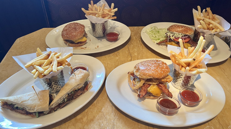 Four plates of Cheesecake Factory burgers and fries.