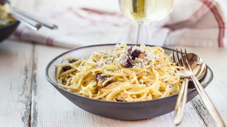A bowl of spaghetti topped with cheese and pepper