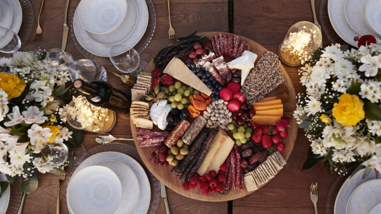 Charcuterie board covered with cheese, meat, and fruits