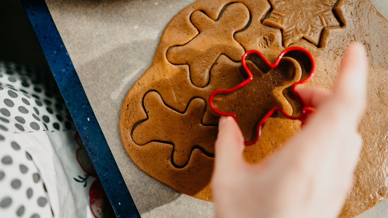 A person using a cookie cutter to make gingerbread people