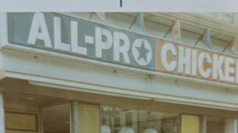 A storefront of all-pro chicken with young Brady Keys Jr. and another man standing in the front.